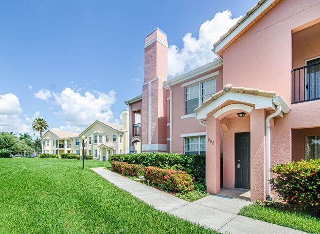 118 Southwest Peacock Boulevard, Unit 10202 Port St. Lucie, FL 34986 - Photo 2 of 11 a front view of a multi story residential apartment building with yard and green space