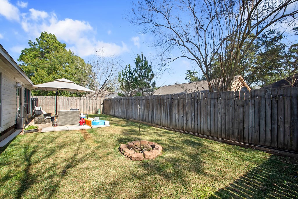 222 Doncaster Street Conroe, TX 77303 - Photo 32 of 33 a view of swimming pool with table and chairs under an umbrella with wooden fence