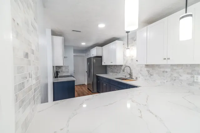 a kitchen with stainless steel appliances kitchen island granite countertop a sink stove and refrigerator