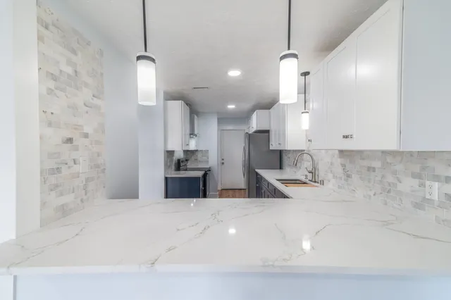 a large kitchen with kitchen island a sink stainless steel appliances and a chandelier