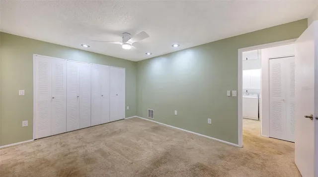 a view of an empty room with window and chandelier fan
