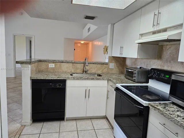 a kitchen with granite countertop a stove sink and cabinets