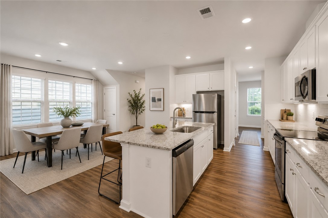 8 Leander Drive Greer, SC 29651 - Photo 9 of 31 An open concept kitchen and dining space with rich wood flooring.