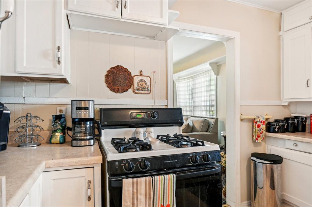 2509 Bird Street Fort Worth, TX 76111 - Photo 7 of 30 a kitchen with a stove and a white wooden cabinets
