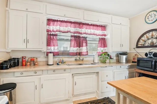 a kitchen with a sink dishwasher a stove and white cabinets with wooden floor
