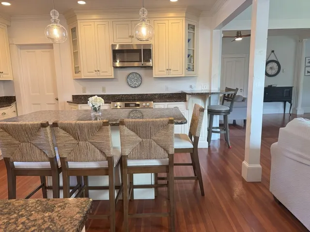 a kitchen with stainless steel appliances granite countertop a table chairs sink and cabinets