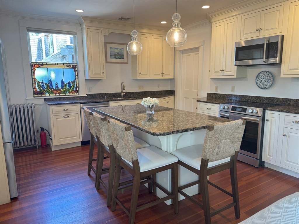 31 South Main Street, Unit 31 Cohasset, MA 02025 - Photo 5 of 30 a kitchen with stainless steel appliances granite countertop a table chairs sink and cabinets