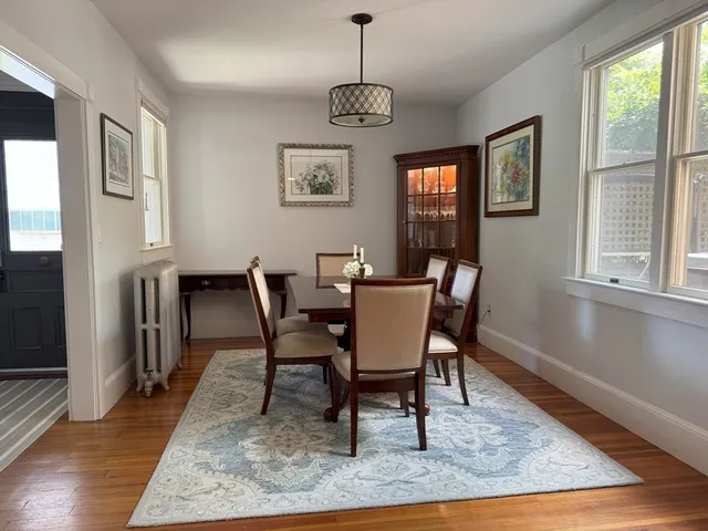 a dining room with wooden floor a chandelier a wooden table and chairs