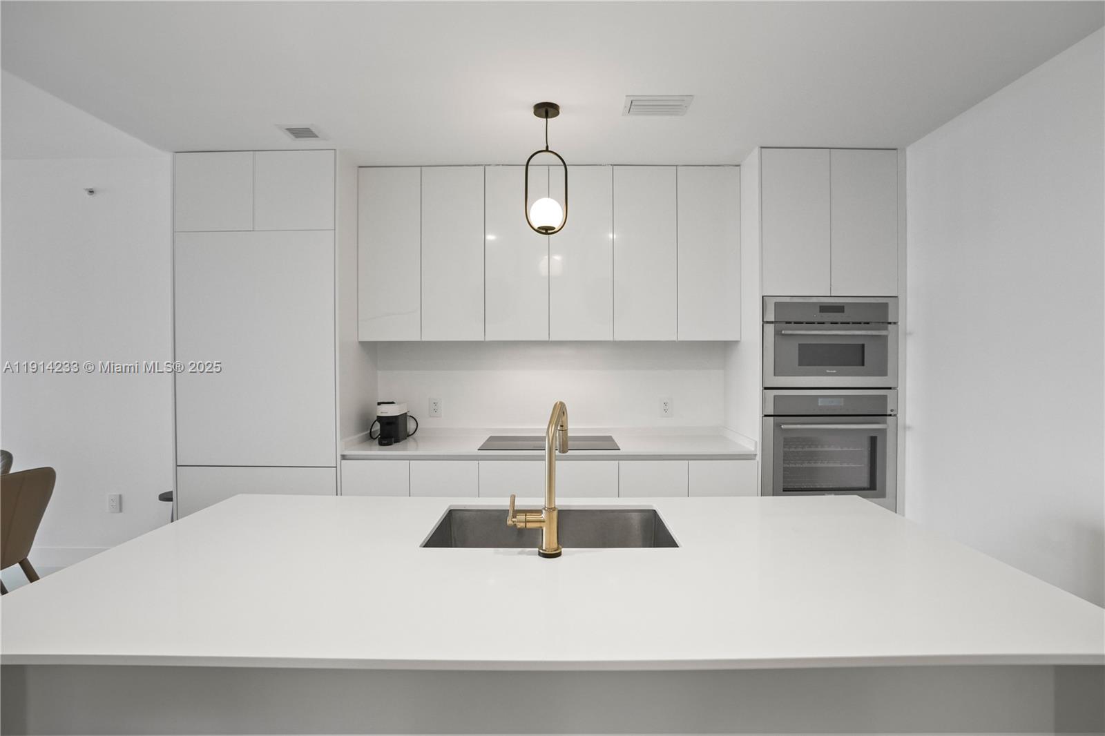 700 Northeast 24th Street, Unit 3905 Miami, FL 33137 - Photo 8 of 46 a kitchen with kitchen island a sink a stove and white cabinets