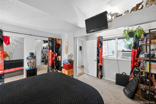 a bedroom with a bed a flat screen tv and a window