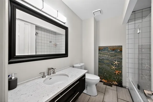 a bathroom with a granite countertop sink toilet and mirror