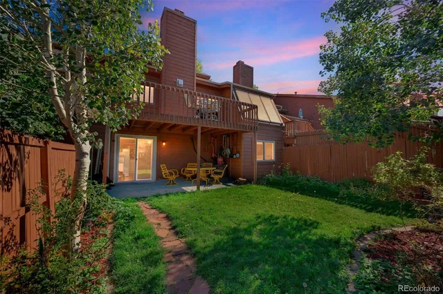 a view of a brick house with a big yard plants and large tree