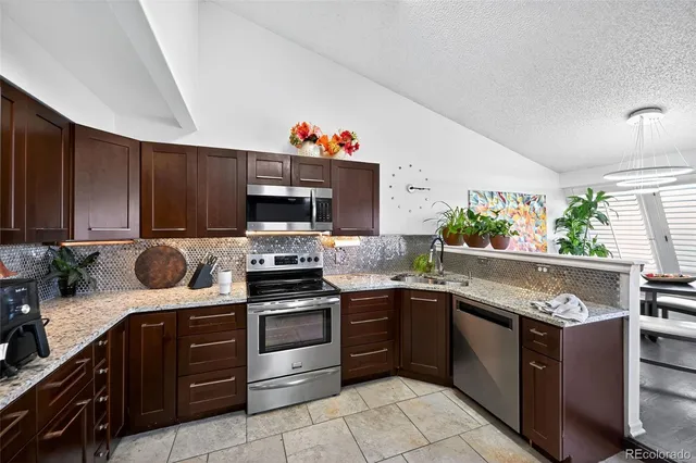 a kitchen with granite countertop a sink stainless steel appliances and cabinets