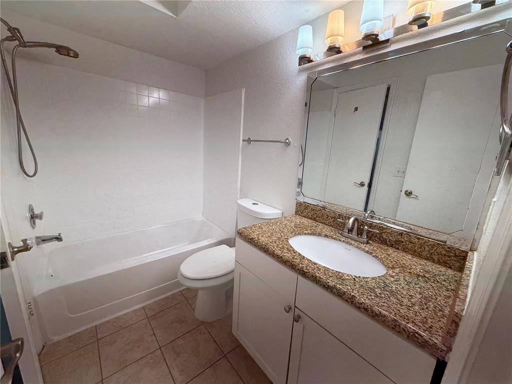 5128 Conroy Road, Unit 25 Orlando, FL 32811 - Photo 16 of 24 a bathroom with a granite countertop sink toilet and shower