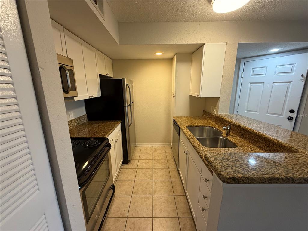 5128 Conroy Road, Unit 25 Orlando, FL 32811 - Photo 5 of 24 a kitchen with stainless steel appliances granite countertop a sink stove and refrigerator