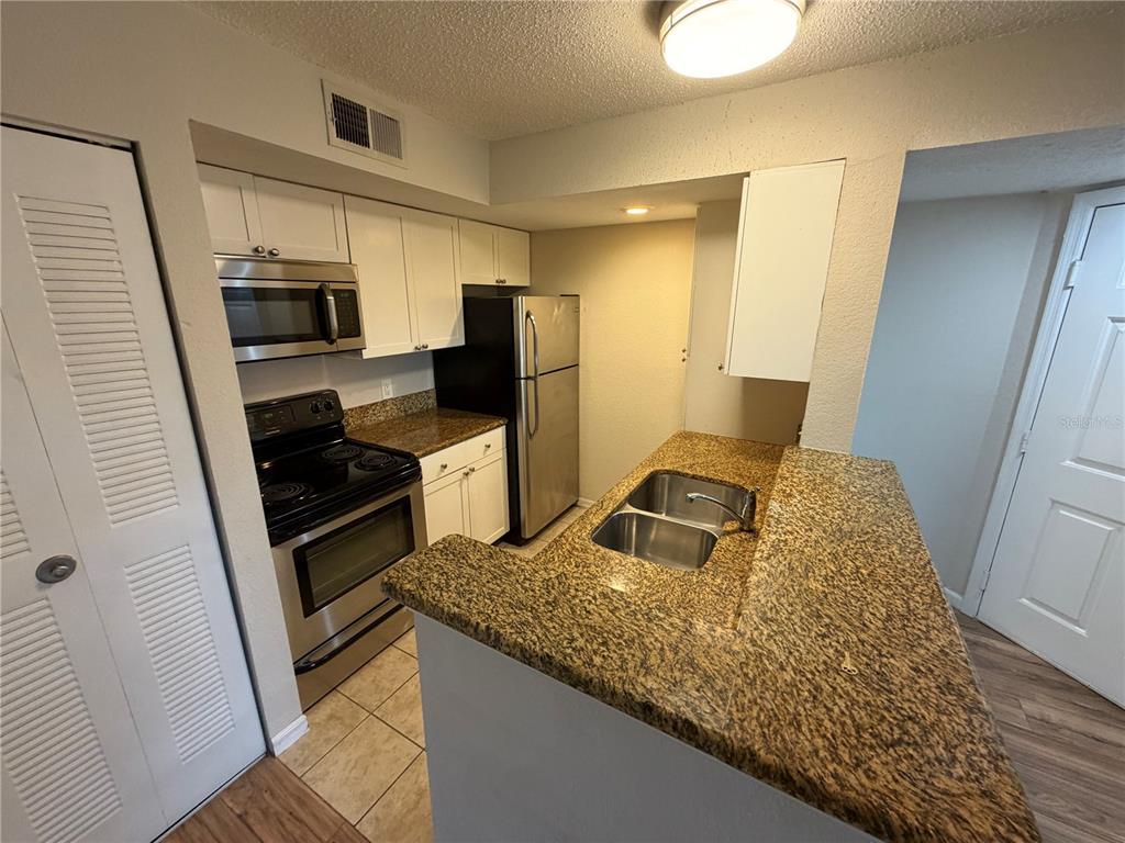 5128 Conroy Road, Unit 25 Orlando, FL 32811 - Photo 6 of 24 a kitchen with stainless steel appliances granite countertop a sink stove and refrigerator