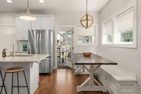 a kitchen with stainless steel appliances granite countertop a refrigerator a sink dishwasher a dining table and chairs with wooden floor
