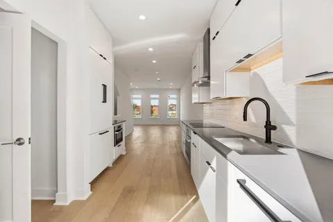 a kitchen with stainless steel appliances a stove a sink and white cabinets