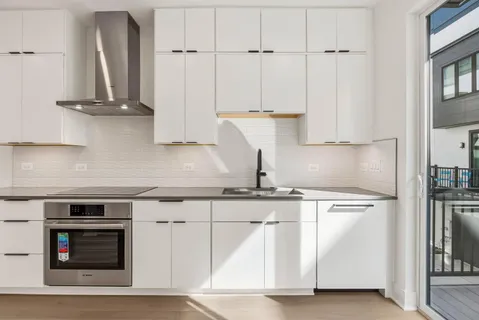 a view of a kitchen with white cabinets and stainless steel appliances