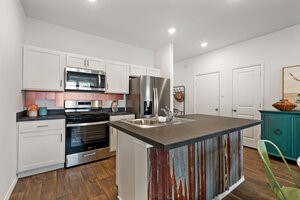 549 Arnold Loop, Unit A Kyle, TX 78640 - Photo 7 of 31 a kitchen with stainless steel appliances wooden floor sink stove microwave and refrigerator