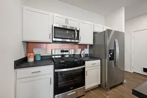 a kitchen with stainless steel appliances wooden floor sink stove microwave and refrigerator