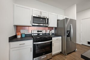 549 Arnold Loop, Unit A Kyle, TX 78640 - Photo 8 of 31 a kitchen with granite countertop white cabinets and stainless steel appliances
