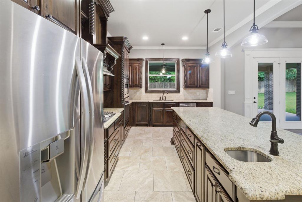 7765 Hickory Spring Lane Tyler, TX 75703 - Photo 19 of 38 Kitchen featuring a large central island with a built-in sink and pendant lighting