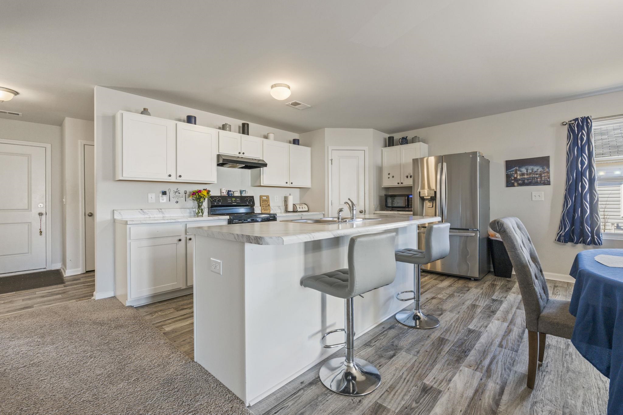 520 Dundalk Drive Conway, SC 29526 - Photo 12 of 35 Kitchen with black appliances, white cabinetry, light countertops, dark wood-style floors, and a kitchen island with sink