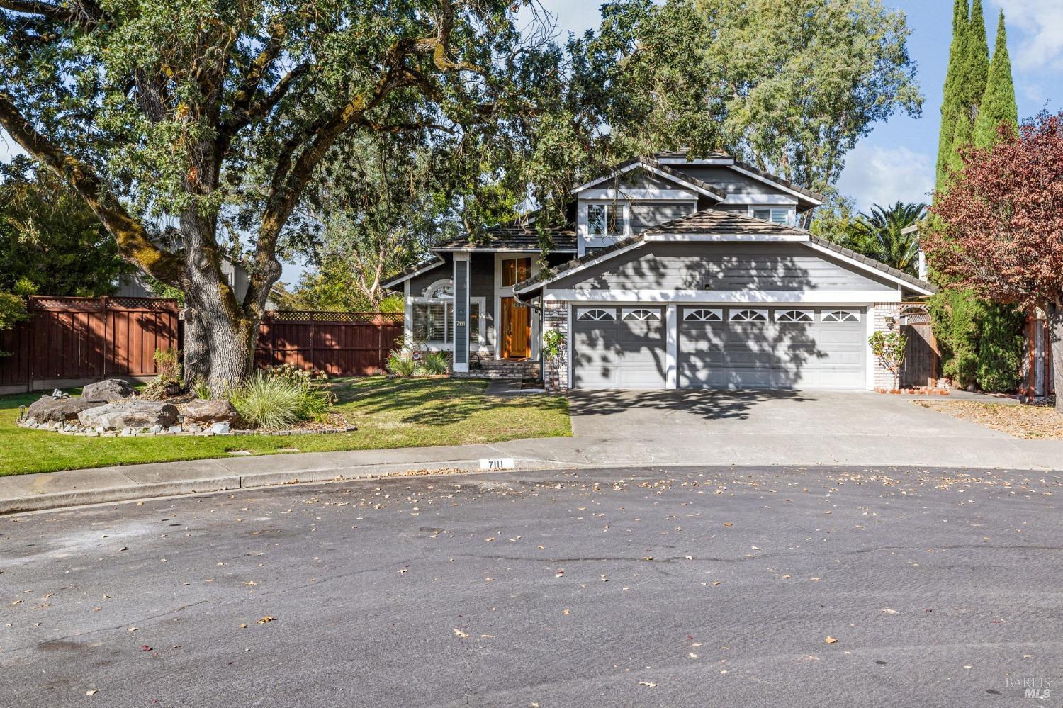 a view of a house with a yard and large trees