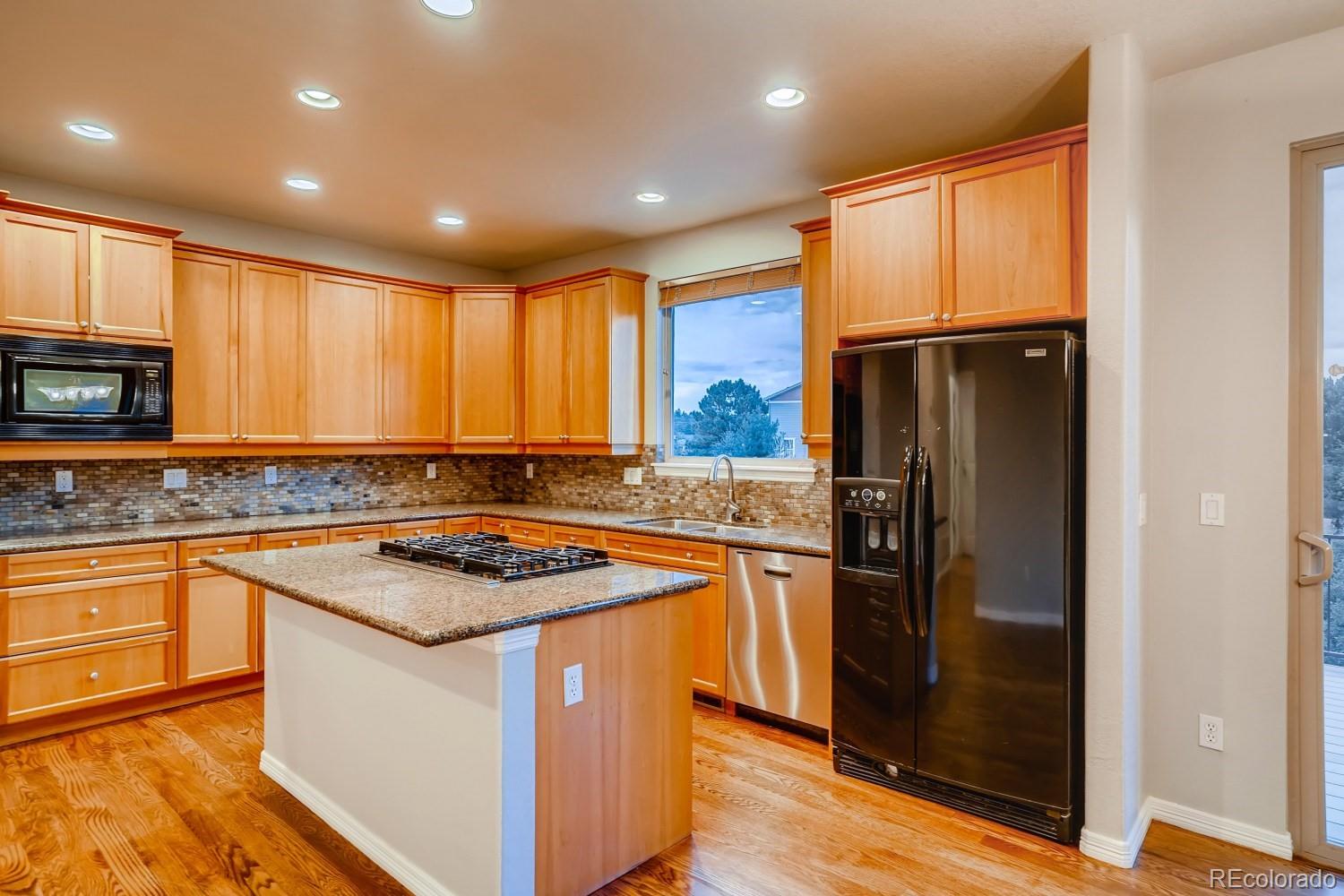 1644 Ridge Trail Lane Castle Rock, CO 80104 - Photo 11 of 38 a kitchen with stainless steel appliances granite countertop a refrigerator a sink dishwasher a stove and white countertops with wooden floor