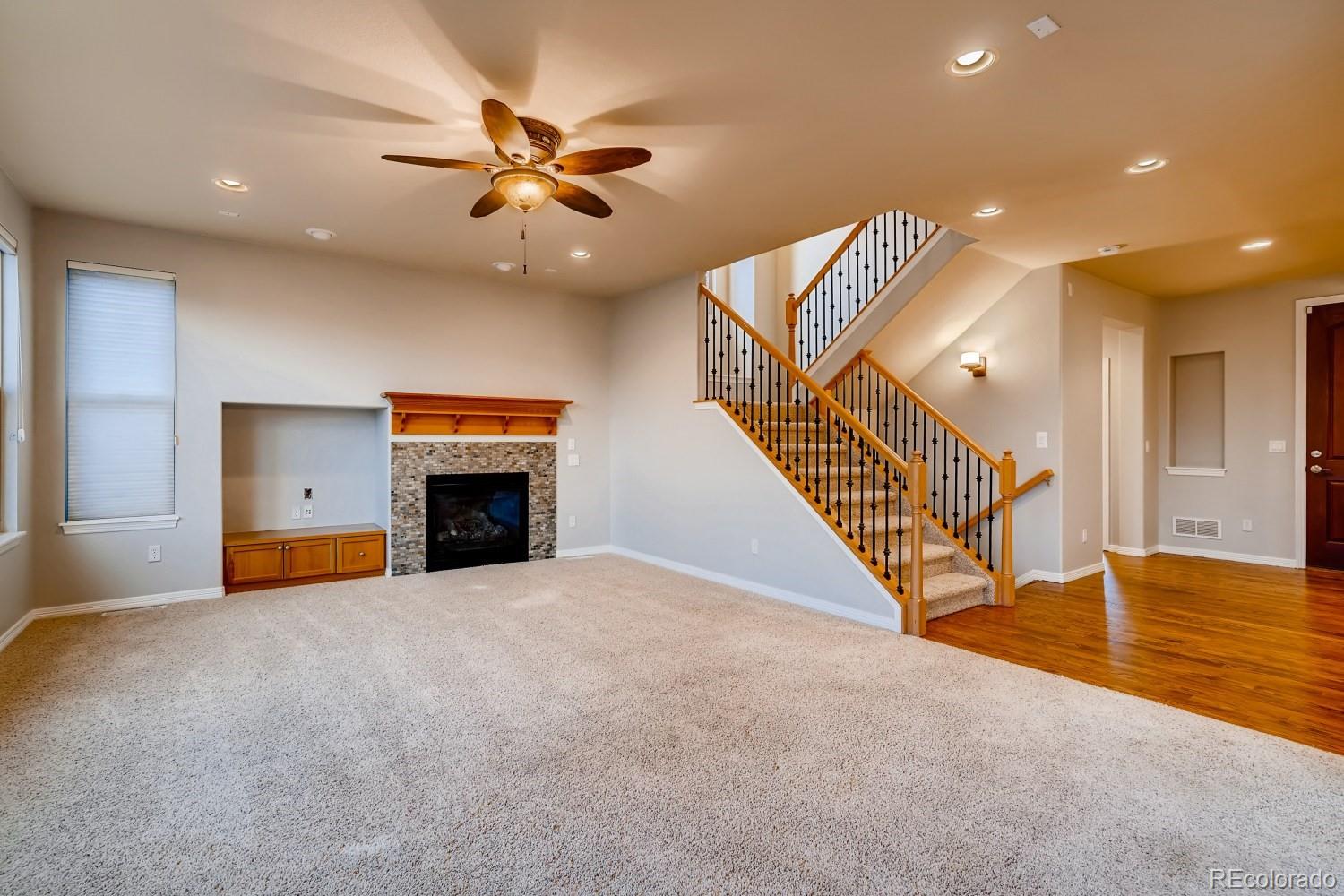 1644 Ridge Trail Lane Castle Rock, CO 80104 - Photo 15 of 38 a view of an empty room with wooden floor a ceiling fan and a fireplace