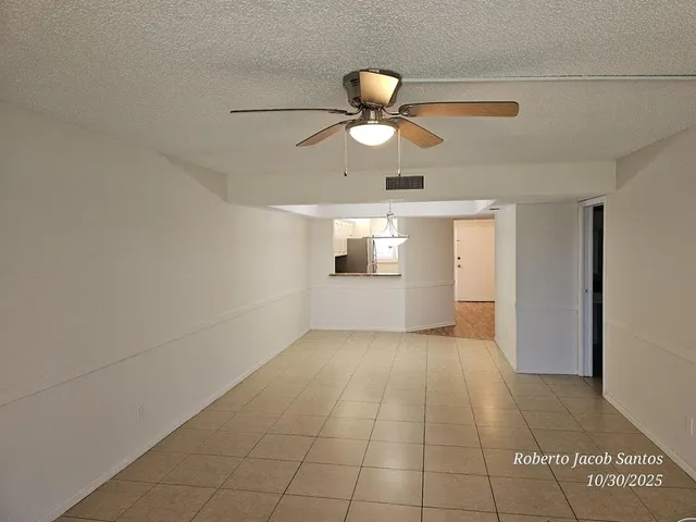 a view of empty room with wooden floor and ceiling fan