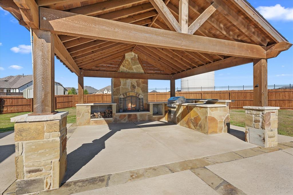 2044 Longbridge Road Forney, TX 75126 - Photo 28 of 40 Covered outdoor entertaining area featuring a stone fireplace, built-in grill, stone-clad counter space, and a wood-beamed ceiling