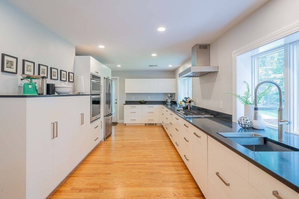 49 Baskin Road Lexington, MA 02421 - Photo 13 of 42 a large kitchen with stainless steel appliances a large counter top a stove a chimney a sink and a large window
