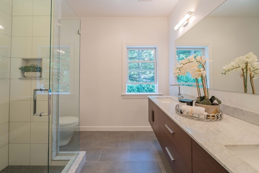 49 Baskin Road Lexington, MA 02421 - Photo 25 of 42 a bathroom with a granite countertop sink a toilet and shower