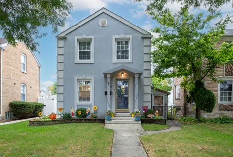 a front view of a house with a yard and potted plants