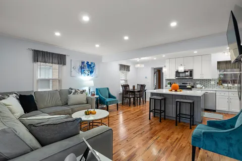 a living room kitchen with furniture and a wooden floor