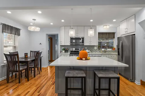 a kitchen with refrigerator a chair and wooden floor