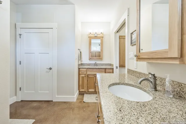 a bathroom with a granite countertop sink and a mirror