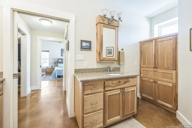 a bathroom with a granite countertop sink two mirror and a refrigerator