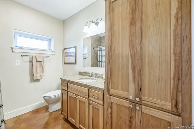 a bathroom with a granite countertop sink a toilet and a mirror