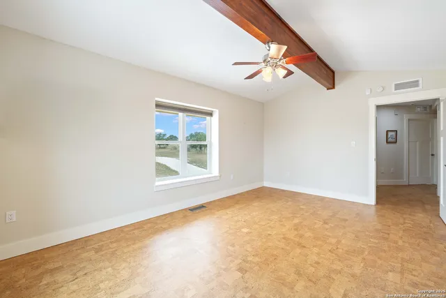 an empty room with windows and fan