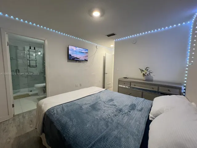 a bedroom with a bed a flat screen tv and dresser