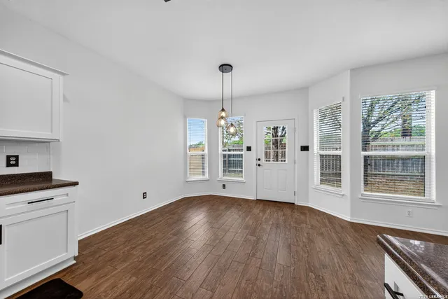 a view of an empty room with a window and wooden floor
