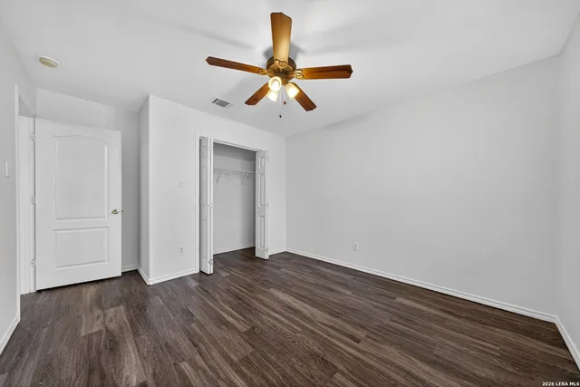 a view of a room with wooden floor ceiling fan and window