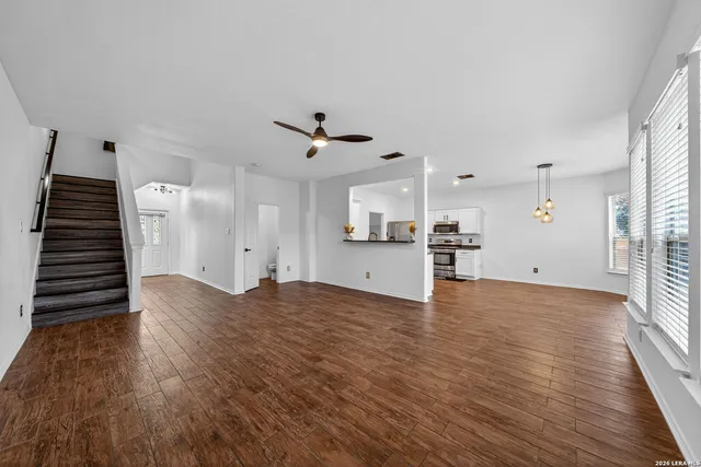 a view of an empty room with wooden floor and stairs