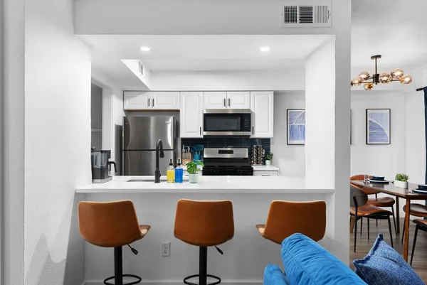 a kitchen with stainless steel appliances granite countertop a dining table and chairs