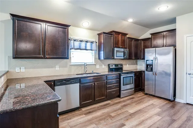 a kitchen with stainless steel appliances granite countertop a stove a sink dishwasher a refrigerator and a oven