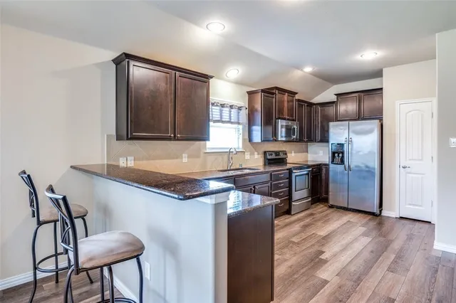 a kitchen with granite countertop a refrigerator stove top oven and sink