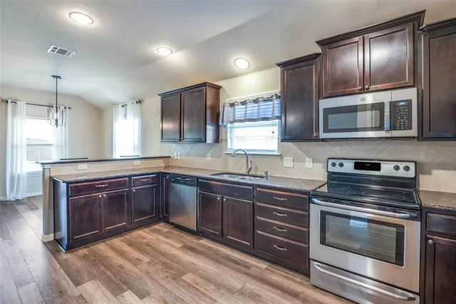 a kitchen with granite countertop wooden cabinets stainless steel appliances and a counter space